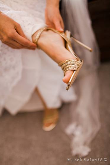 bride getting ready - wearing golden shoes on long heel
