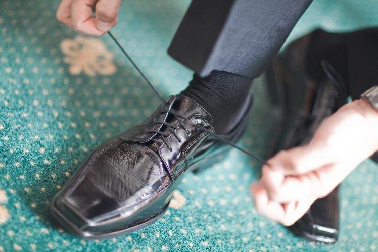 Zaväzovanie topánok čierne lakovky na svadbe prípravy ženícha